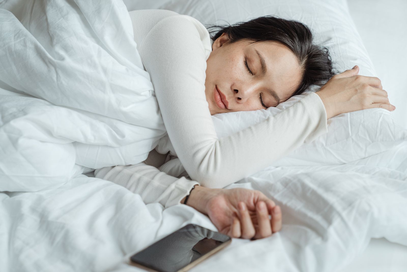 白いリネンに包まれて穏やかに眠る女性